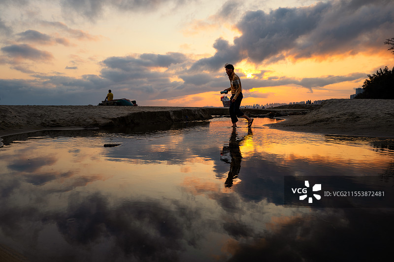 落日余晖中赶去修补渔船的渔民图片素材