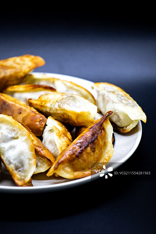 黑色背景下白色盘子中的中国传统美食小吃牛肉锅贴面食特写图片素材