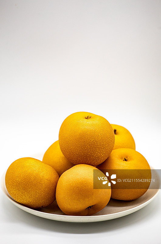 白色背景白色盘子中的山东烟台莱阳特产秋月梨水果特写镜头图片素材