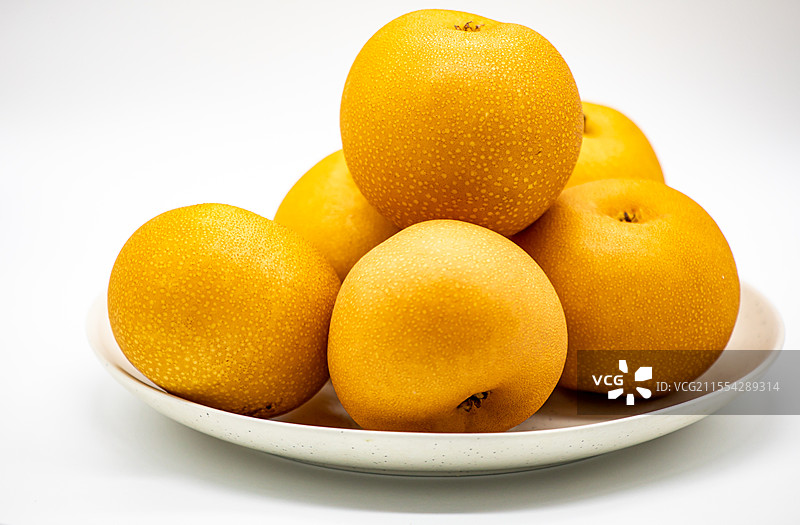 白色背景白色盘子中的山东烟台莱阳特产秋月梨水果特写镜头图片素材