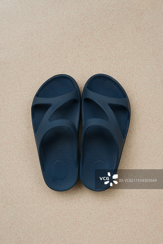 淡粉色地砖上的一双藏青色拖鞋图片素材