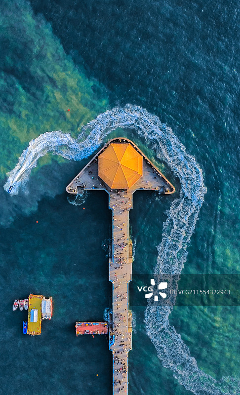 山东青岛高视角航拍栈桥景区，清澈蔚蓝的海面上，一艘船划出了一道优美弧线，构成了独特的景色。图片素材