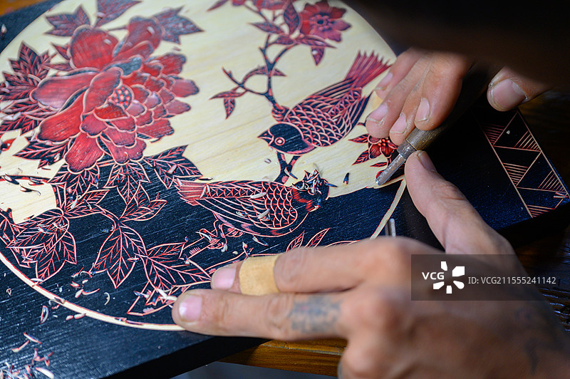 一双正在雕刻木板花鸟画的手图片素材