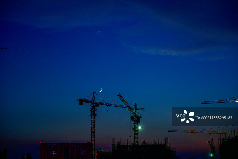 夜幕下新月映照的塔吊工地图片素材