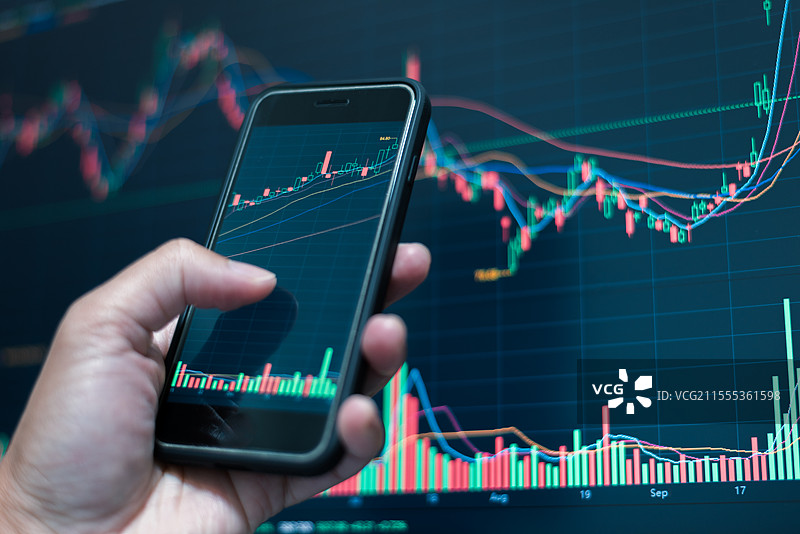 使用手机和电脑研究股市走势图片素材