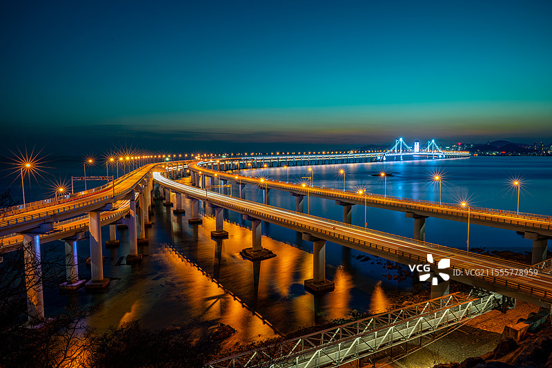 长桥披霞车灯流，河面倒影染金辉图片素材