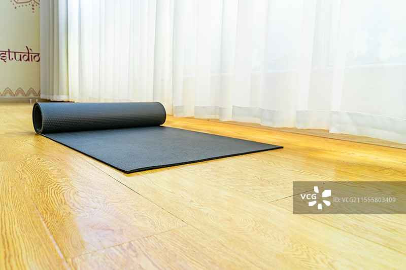 中国室内的瑜伽馆，木地板上，白色的窗帘，木质地板上的放置展开黑色的瑜伽垫，室内无人图像摄影图片素材