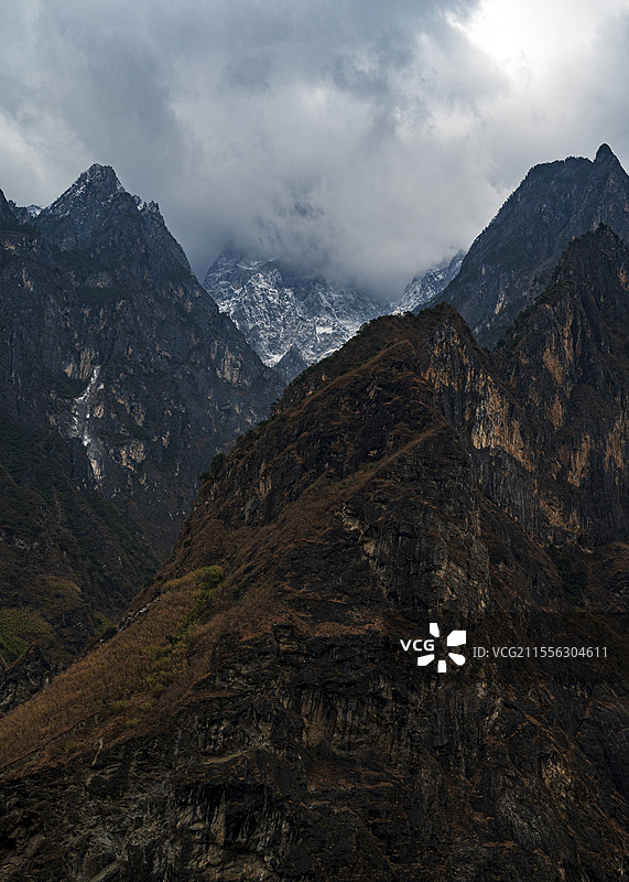 乌云中隐隐约约能看到虎跳峡山谷缝隙中显现出的玉龙雪山图片素材