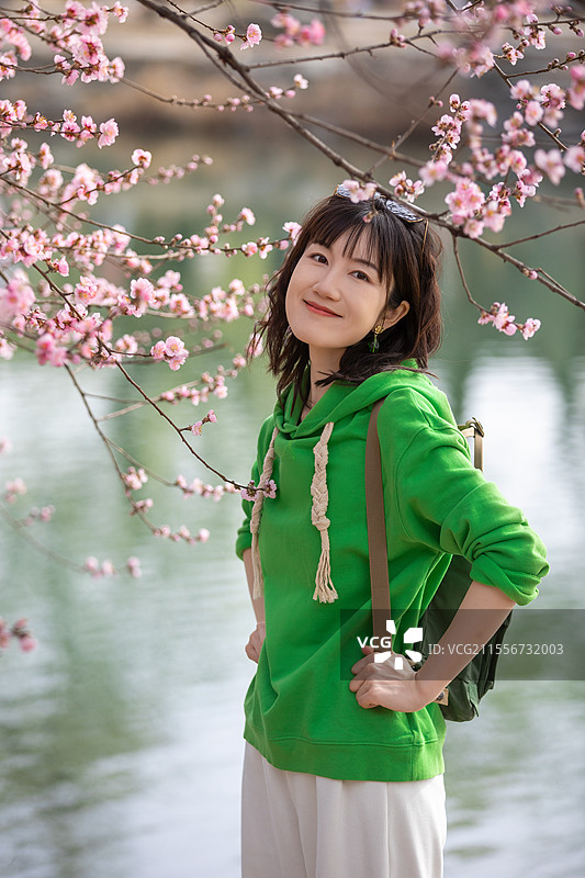 站在樱花树旁的年轻女子，春天站在花枝下的少女，美女，人像，春天，樱花，桃花，踏青，春游图片素材
