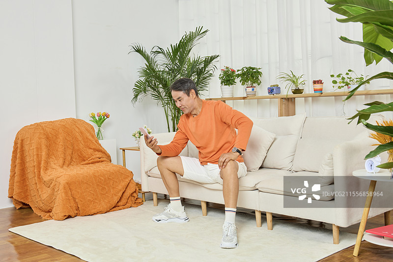 低头看手机微笑的老年男性图片素材