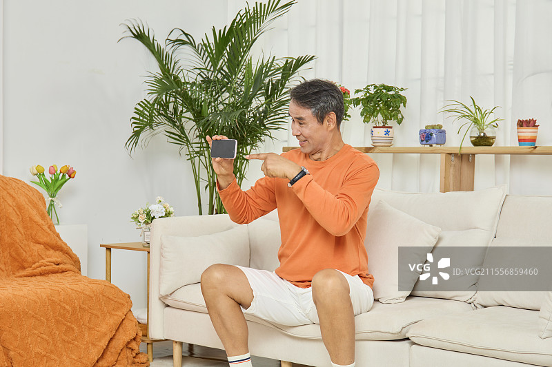 手拿手机进行推荐介绍的老年男人图片素材