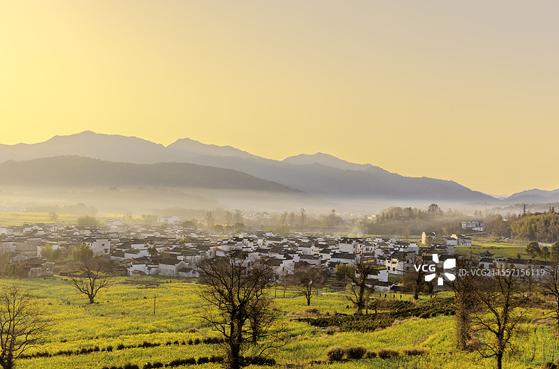 安徽徽州黟县卢村日出晨雾与油菜花和徽派建筑图片素材