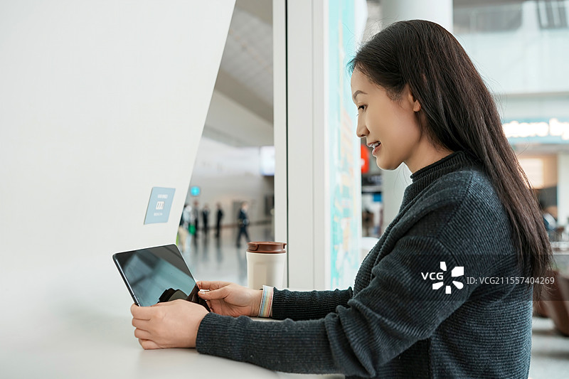 现代公共空间中与平板电脑互动的年轻女性图片素材