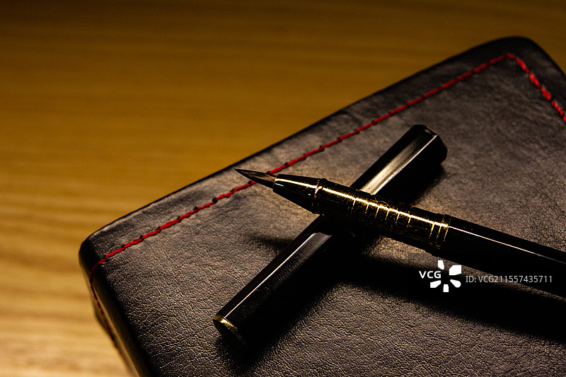 昏黄的台灯照亮的桌面上的笔和本子图片素材