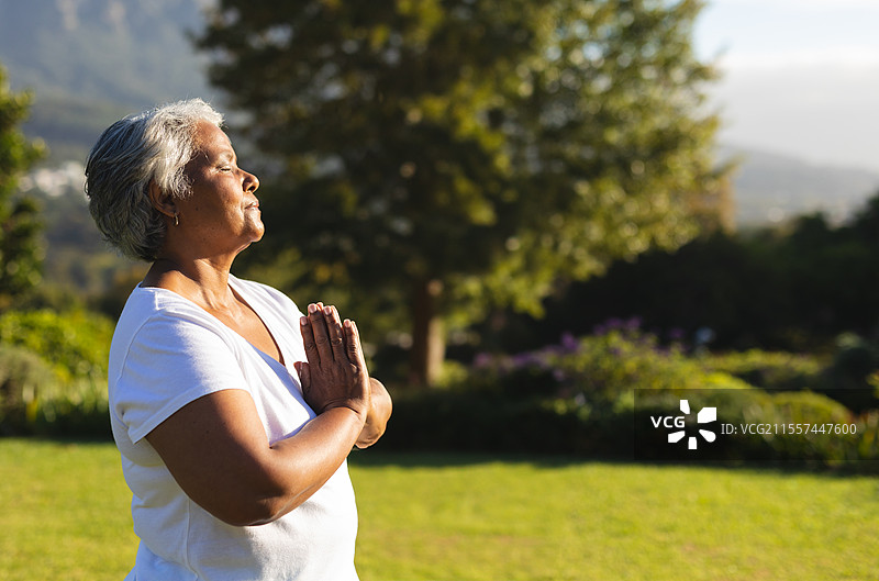 在宁静的花园中冥想的老年女性，享受晨光，留有空白空间图片素材