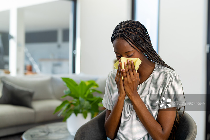 在家中坐在椅子上的女性，打喷嚏用纸巾，感到不适，留白空间图片素材