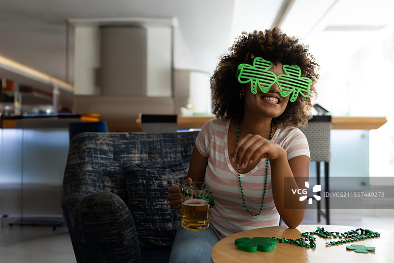 戴着三叶草眼镜的女人在家派对上享受啤酒并大笑，留白空间图片素材