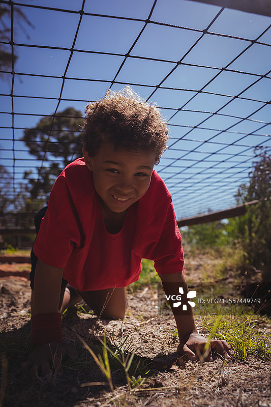 孩子在户外爬过网，面带微笑，享受训练营活动图片素材