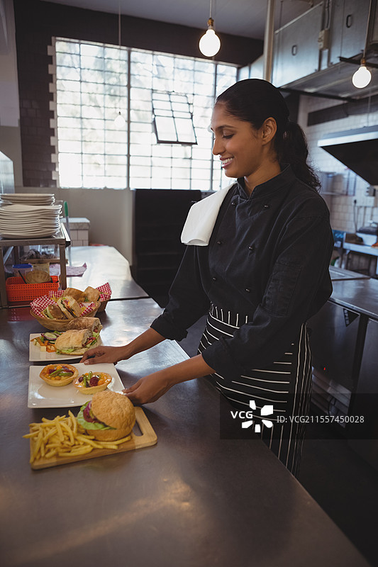 厨师在现代咖啡馆厨房准备美味的美食汉堡和薯条，留白空间图片素材