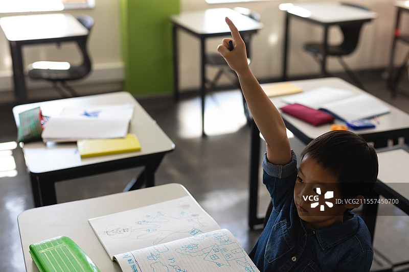 在学校，年轻男孩在教室里举手，渴望回答问题，留白空间图片素材