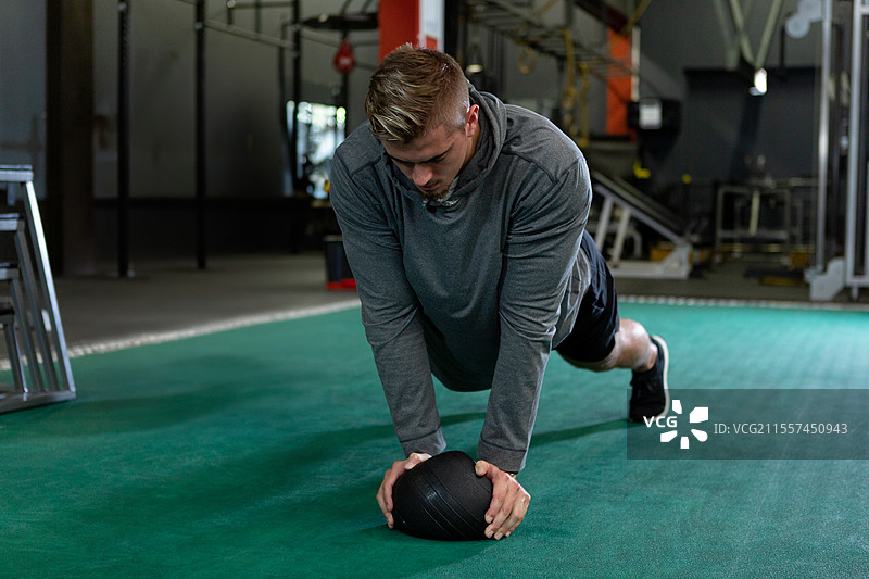 健身房里，运动员在健身球上做平板支撑，专注于力量训练图片素材