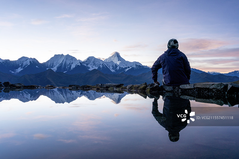 一个人背影坐在湖边倒影看贡嘎雪山图片素材