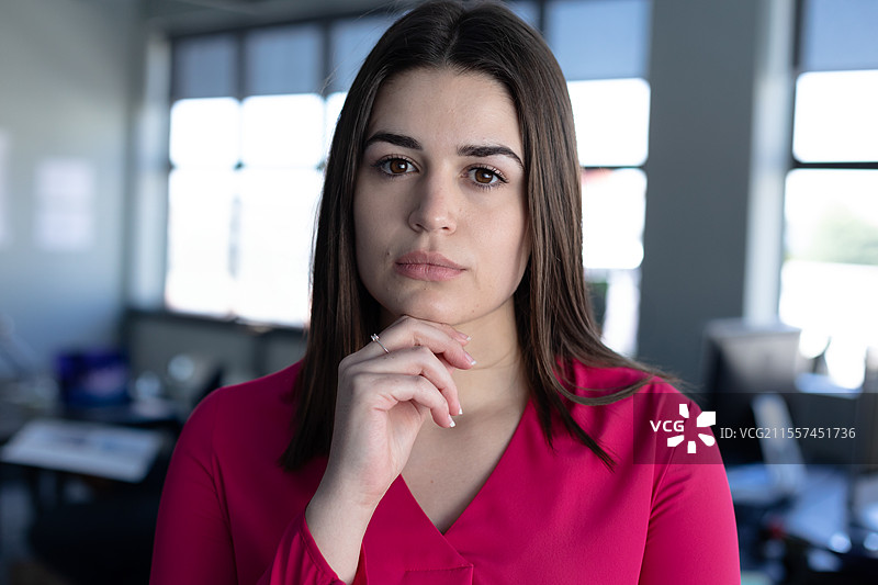 自信的女商人在现代办公室环境中穿着粉色衬衫思考图片素材