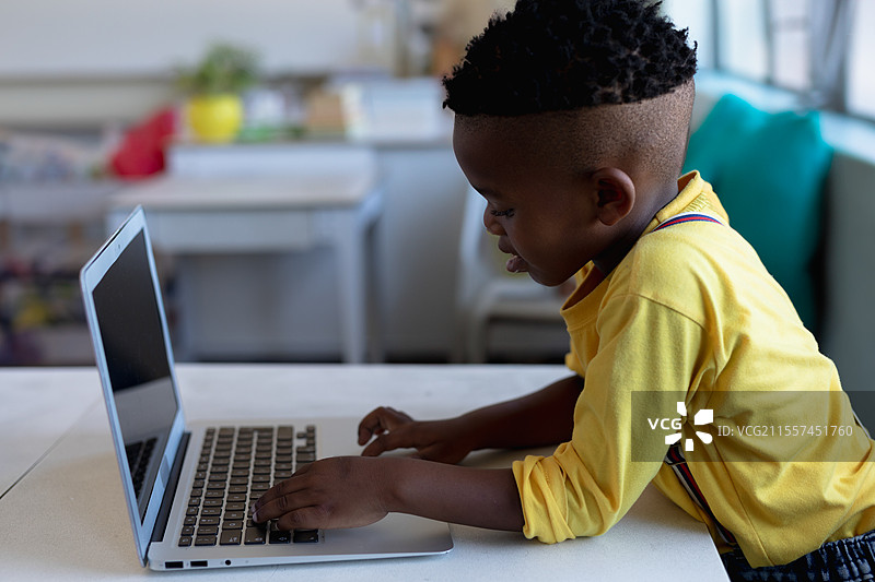 年轻男孩在教室里使用笔记本电脑，专注于学校项目图片素材