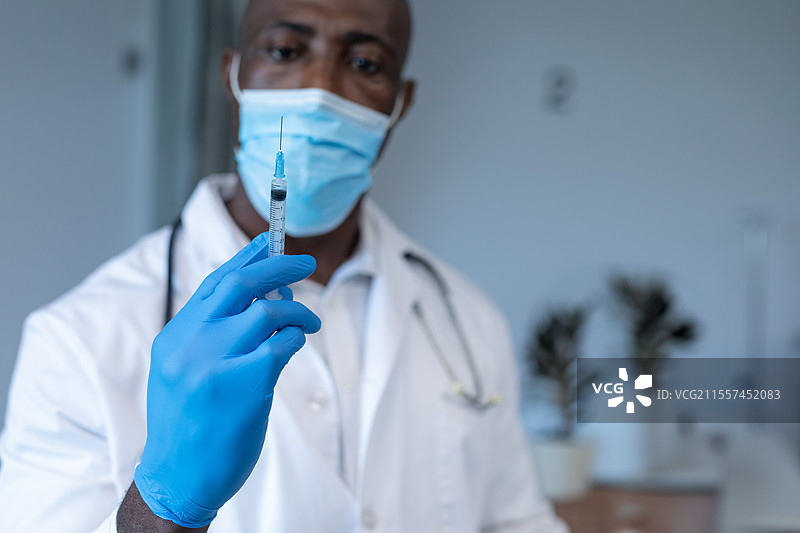 戴着口罩和手套的医生手持注射器，准备进行疫苗接种图片素材