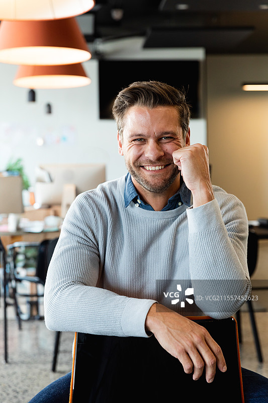 微笑的男士在办公室靠着椅子，显得自信且平易近人图片素材