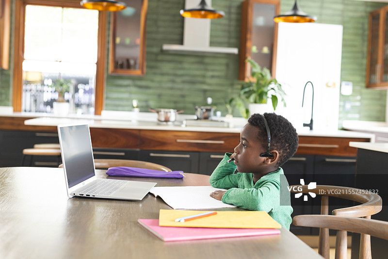 年轻男孩在家在线学习，专注于笔记本电脑并做笔记图片素材