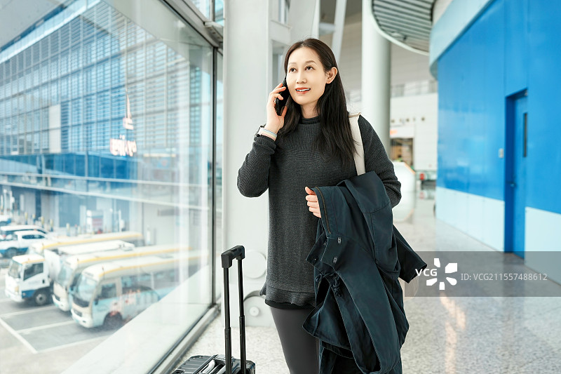 年轻女子在机场旅行时打电话图片素材