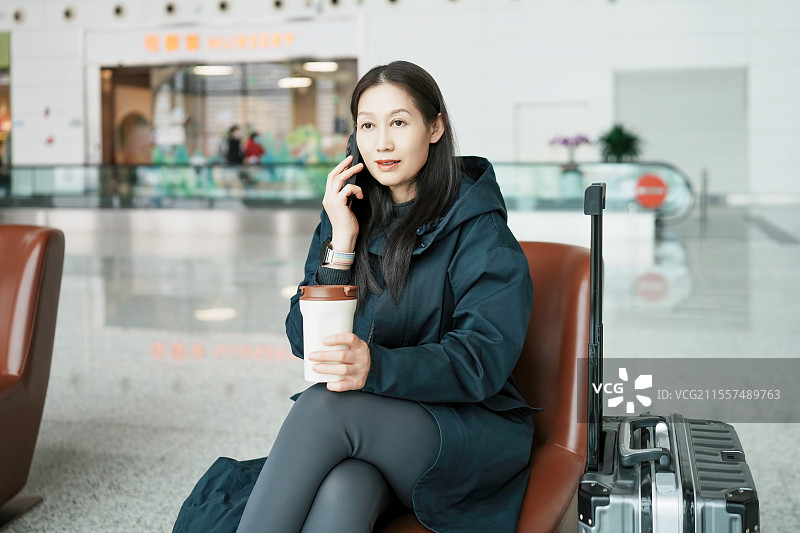 年轻女子拿着咖啡和行李在机场等候图片素材