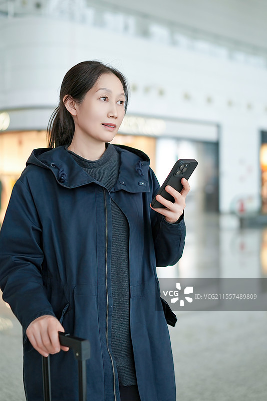 在机场拿着智能手机的女人，准备旅行和冒险图片素材