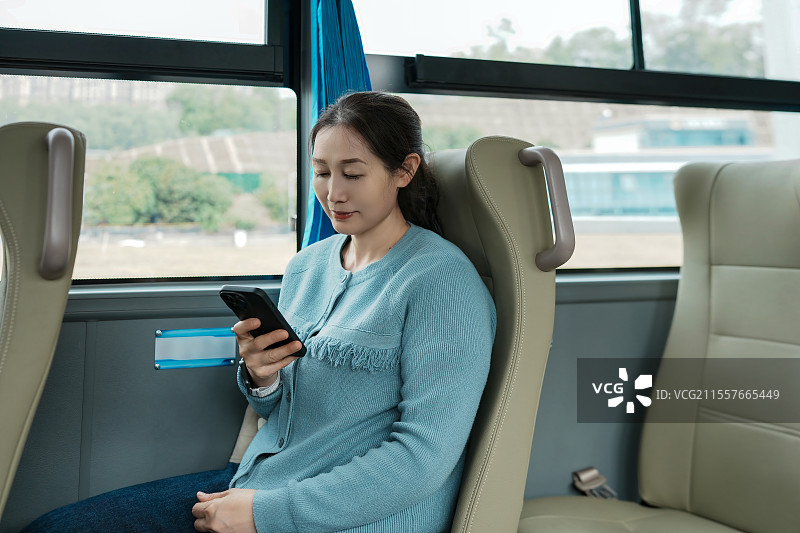 年轻女子在公共汽车上旅行时使用智能手机图片素材