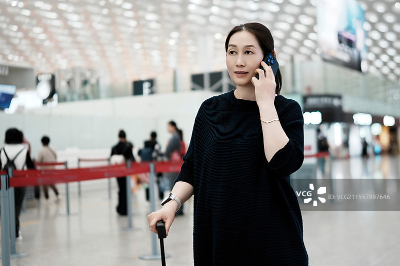 年轻女子在机场办理登机手续时正在打电话图片素材