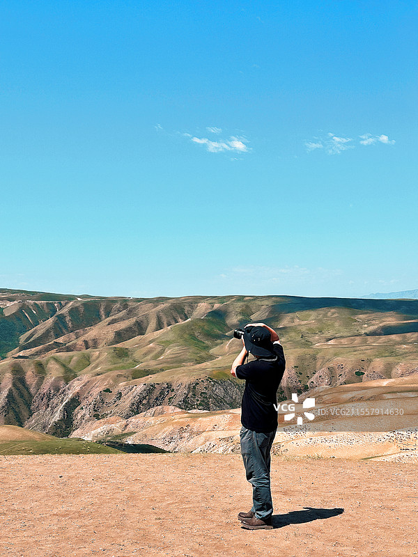 蓝天山谷上拍照的男人图片素材