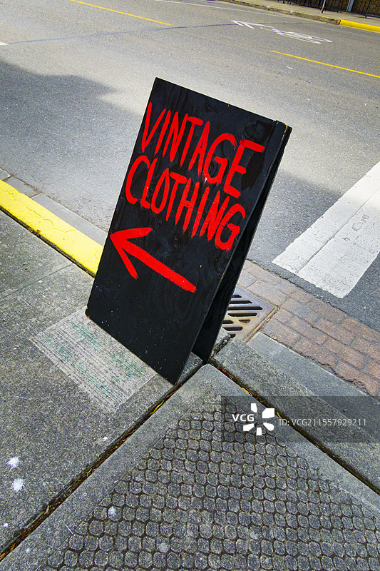 商店标识，美国，复古服装店的A型招牌， sidewalk上的黑板上用红色字迹写着“复古服装”，并有一个指向箭头。图片素材