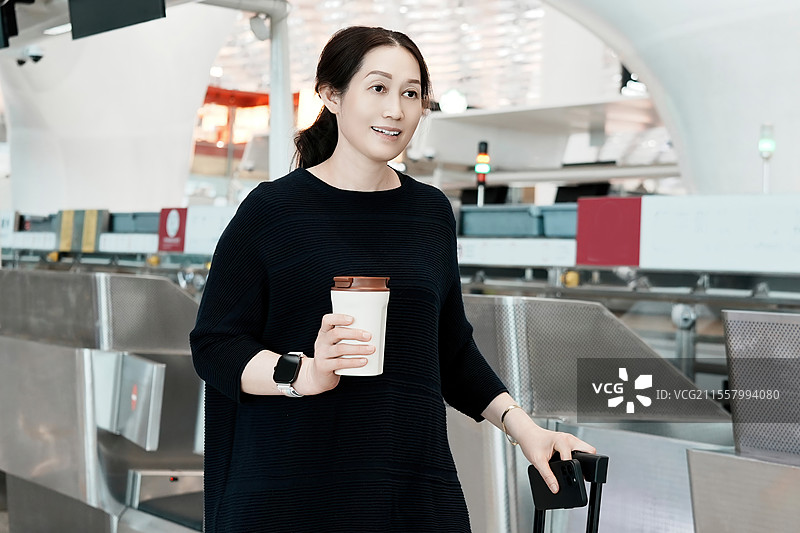 女士在机场值机柜台拿着咖啡和行李图片素材