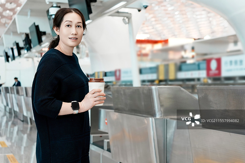 女士在机场值机柜台拿着咖啡和行李图片素材