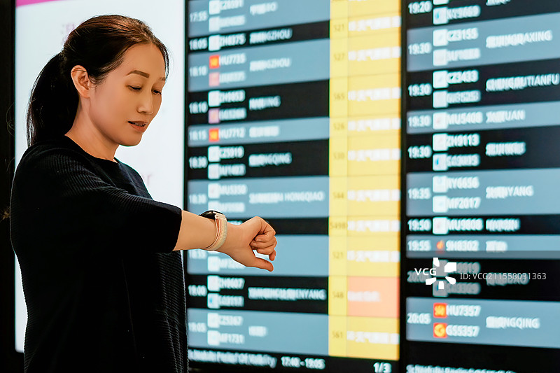年轻女子在机场查看航班时刻表图片素材