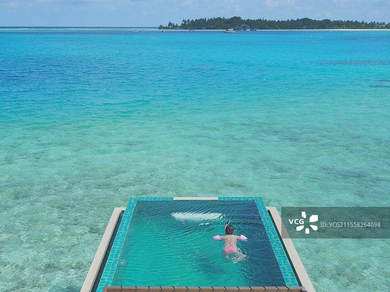 马尔代夫薇拉瓦鲁度假岛游泳池中女性的高角度视角图片素材