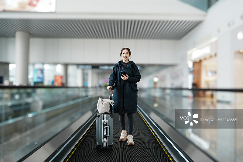 年轻女子带着智能手机和行李在机场旅行图片素材
