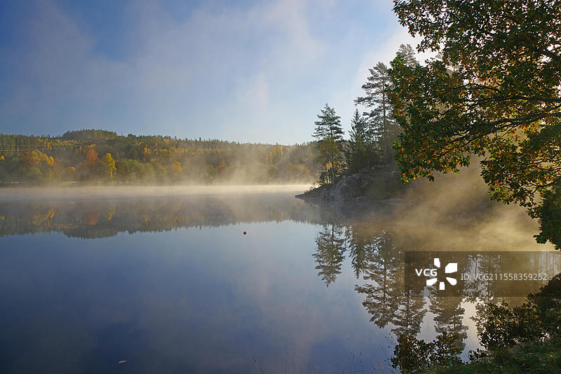 平静湖面上的日出和秋季晨雾，树叶变色，布拉伦，博胡斯兰，瑞典图片素材