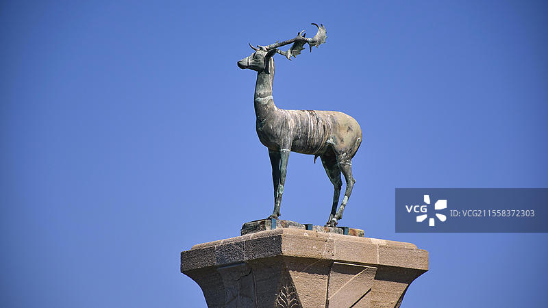 青空下的青铜鹿雕像，位于罗德镇的曼德拉基港口的基座上，罗德岛，多德卡尼斯群岛，希腊，欧洲图片素材