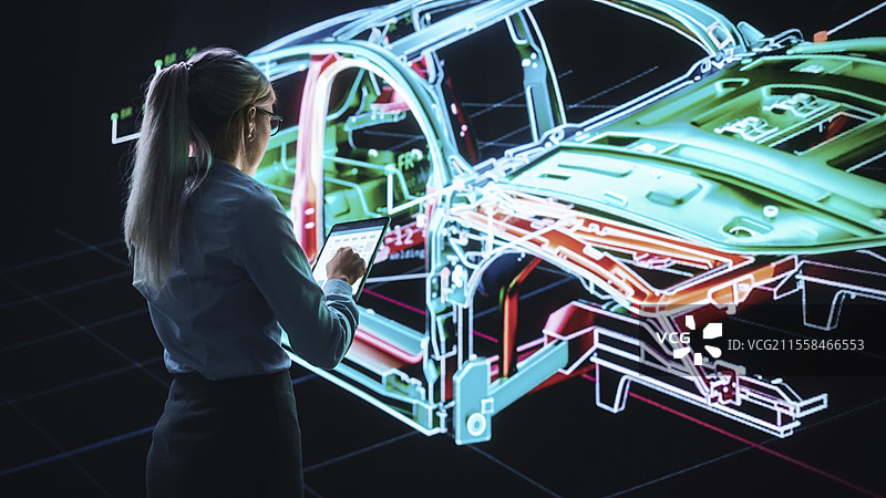 工程师使用平板电脑和墙面屏幕设计电动汽车图片素材