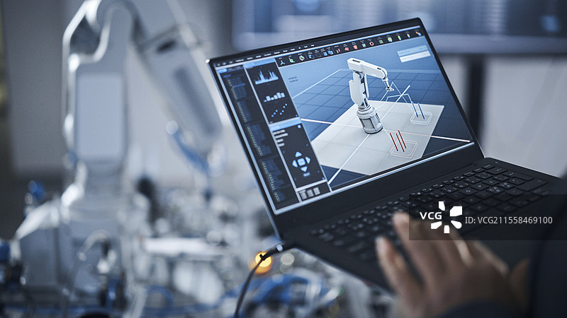 工程师使用笔记本电脑设计机器人手臂图片素材