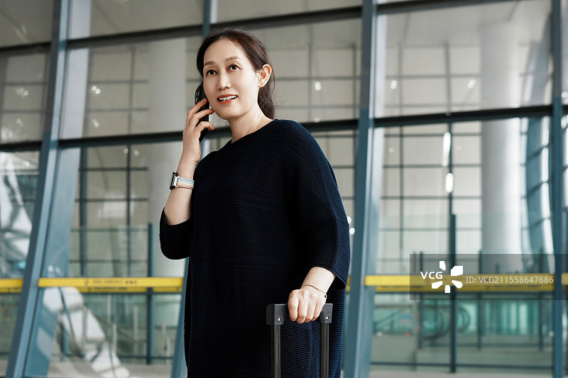 自信的女人在旅行时使用智能手机打电话图片素材