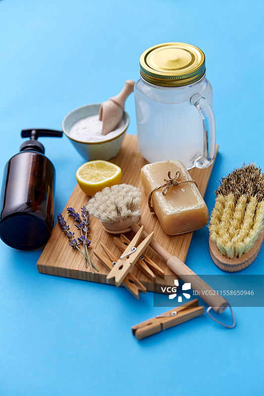 天然清洁用品与生态生活理念 - 洗衣苏打、洗衣液和肥皂、木夹子，配有刷子和柠檬，背景为蓝色。洗衣苏打、肥皂、刷子、柠檬和夹子。图片素材