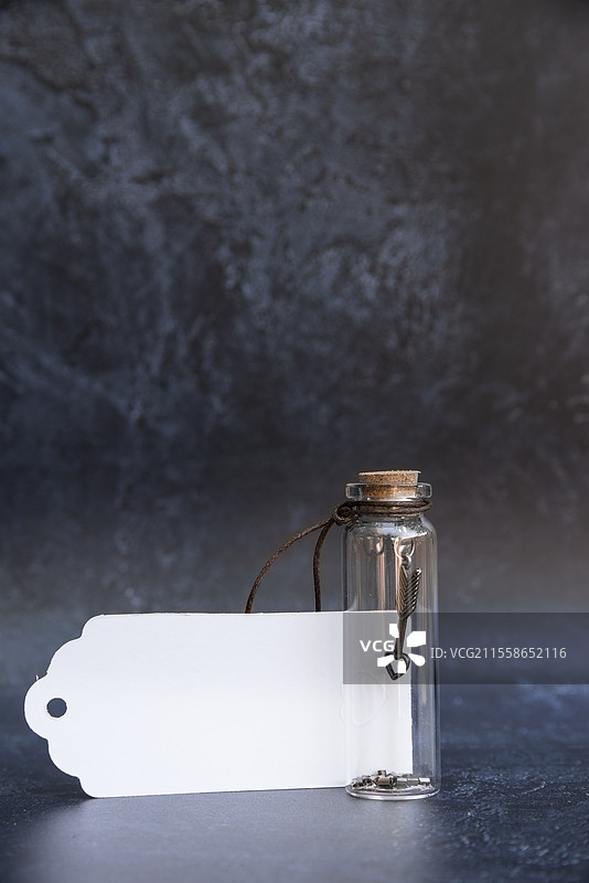 浪漫的复古玻璃许愿瓶，瓶内有好运符，配有软木塞和古董效果背景，以及空白标签供书写文本。图片素材